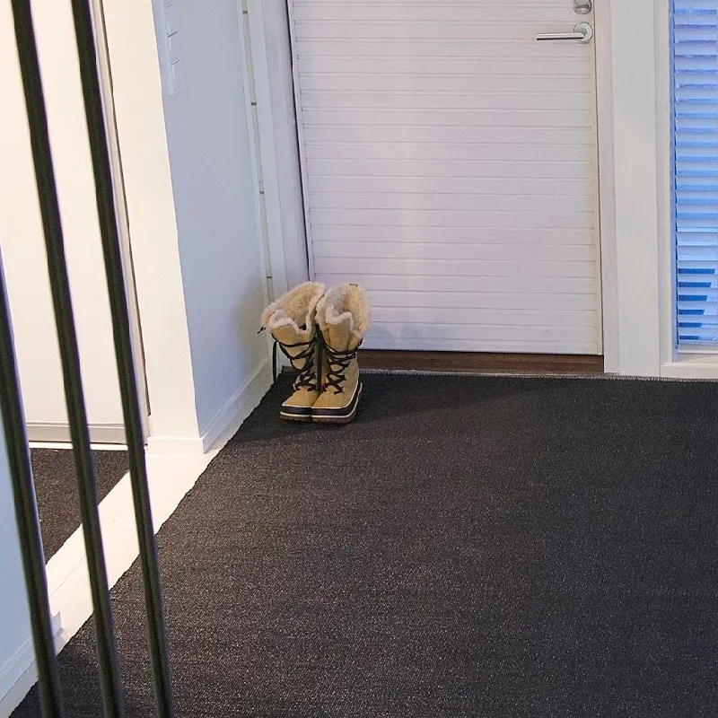 Dark outdoor mat with snow boots on it.