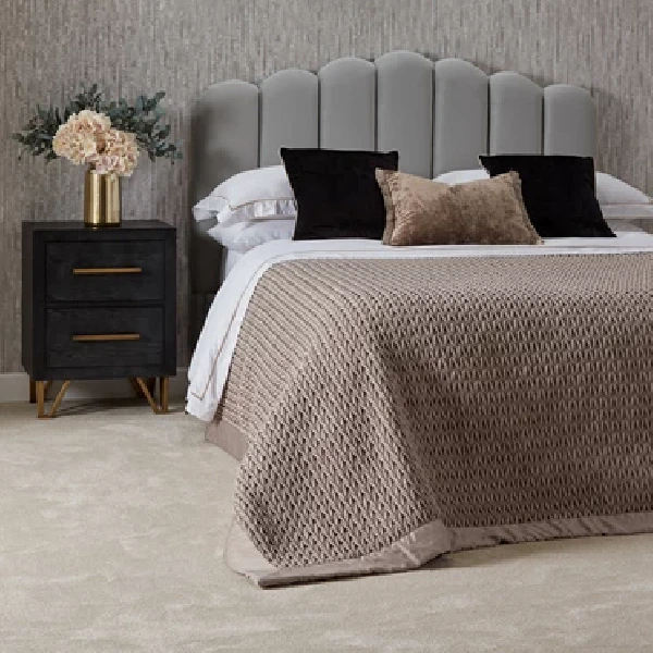 neutral-toned bedroom with a light gray carpet, a bed with a gray scalloped headboard